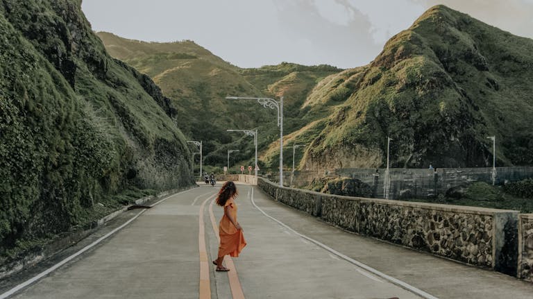 A woman strolls on a scenic mountain road in Cagayan Valley, Philippines.